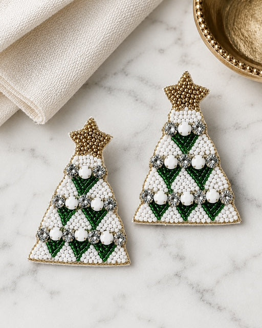 Green beaded Christmas tree statement earrings with gold star tops on a white marble background