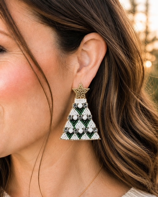 Woman wearing green beaded Christmas tree statement earrings with gold star tops