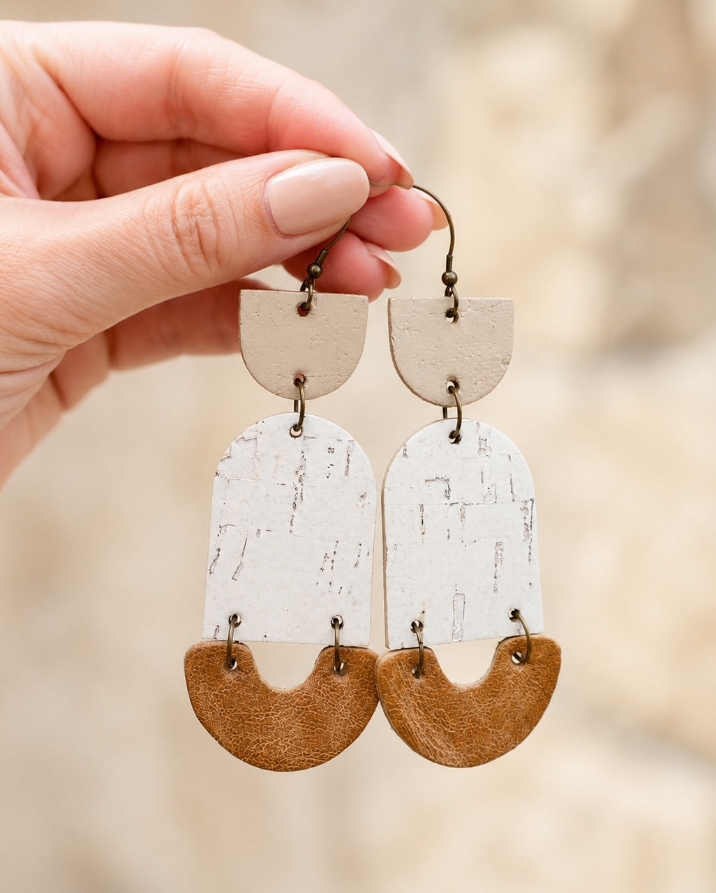 Hand holding Golden Birch handmade cork and leather earrings to show size and layered texture.