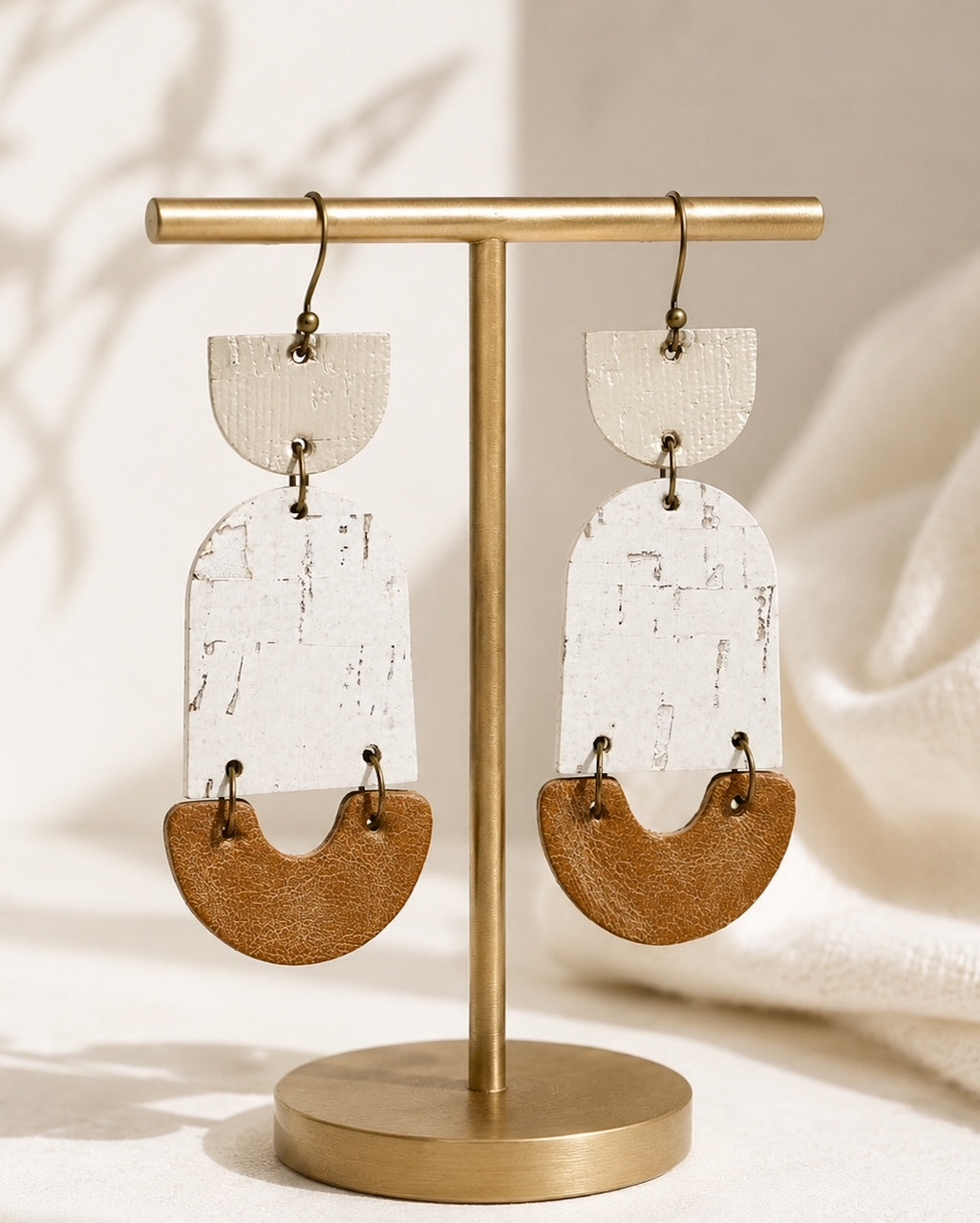 Golden Birch neutral statement earrings displayed on a matte gold jewelry stand.