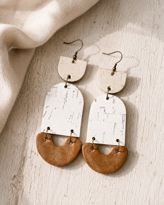 Golden Birch handmade cork and leather earrings on a light wood surface.
