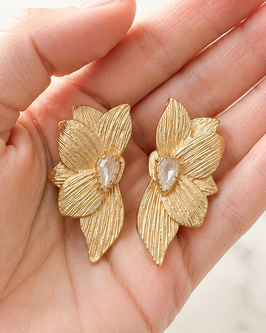 Golden Magnolia Studs gold flower earrings shown in hand for size reference.