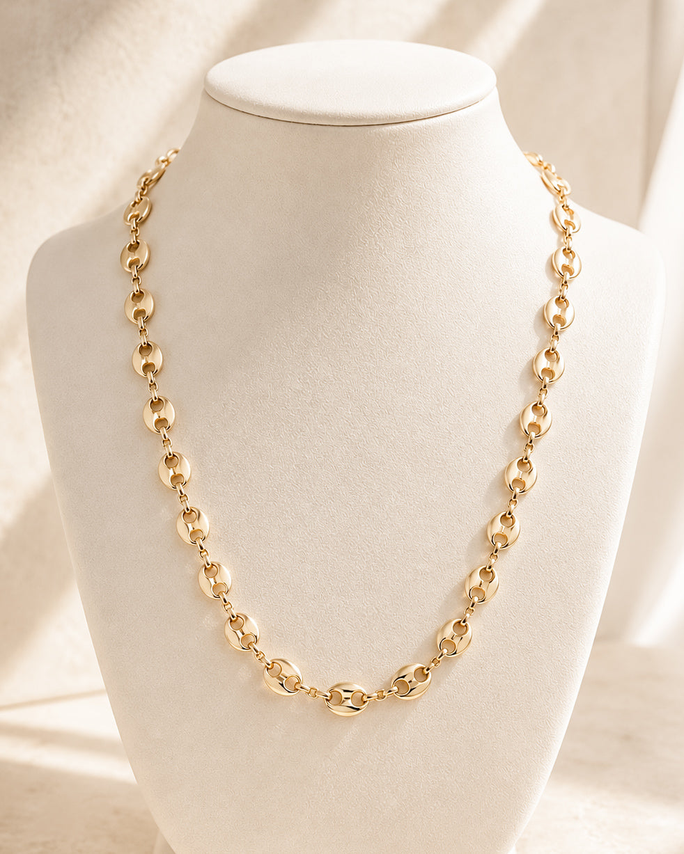 Front view of the Golden Together Necklace on a cream jewelry display, showing the 16-inch gold-tone chain with repeating oval links.