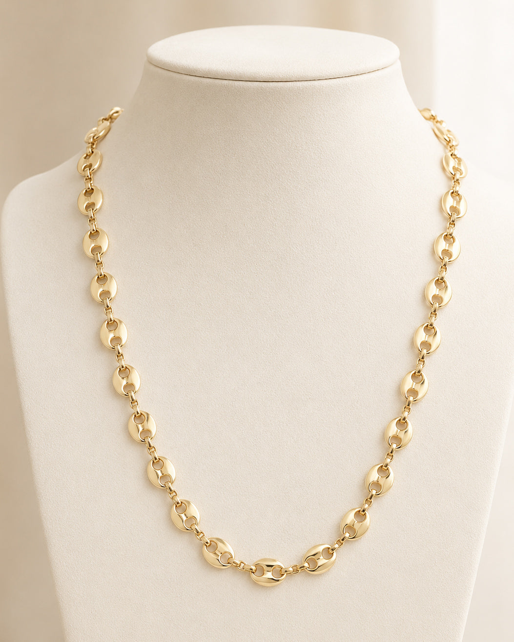 Golden Together Necklace displayed on an ivory jewelry bust, featuring polished gold-tone oval links in a trendy, delicate chain design.
