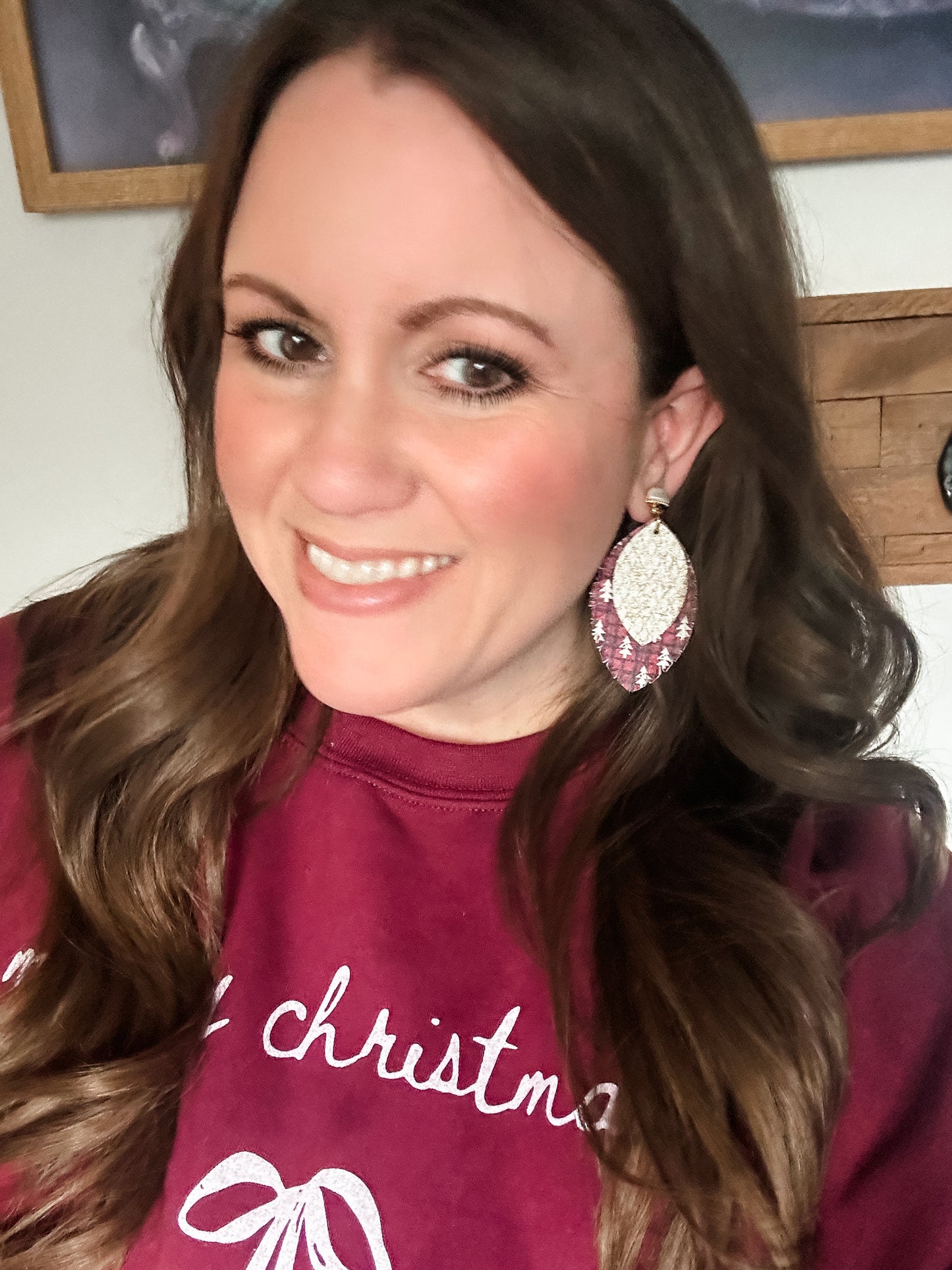 Woman wearing Golden Noel earrings with pearl studs and layered plaid and gold leather while dressed in a cranberry Merry Christmas sweatshirt.
