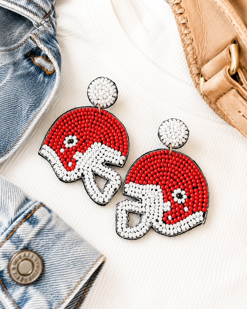 Red football helmet seed bead earrings styled with an ivory sweater, denim jacket, camel purse, and gold accessories.