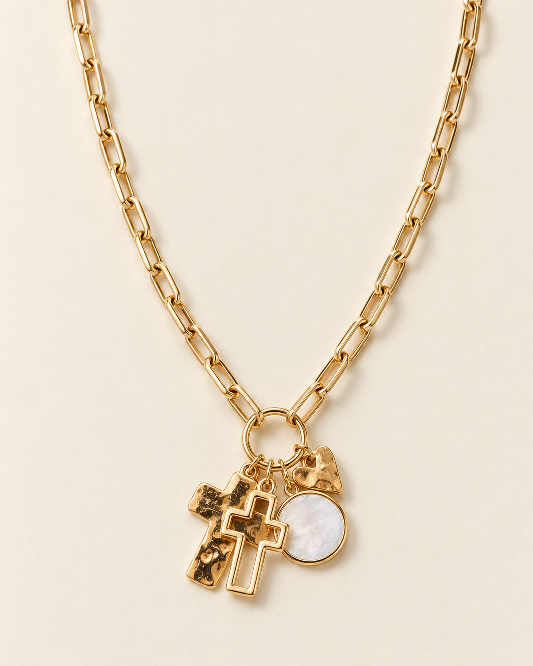 Heart & Soul gold charm necklace with two layered crosses, a textured heart, and a pearly round pendant hanging from a chunky paperclip chain.