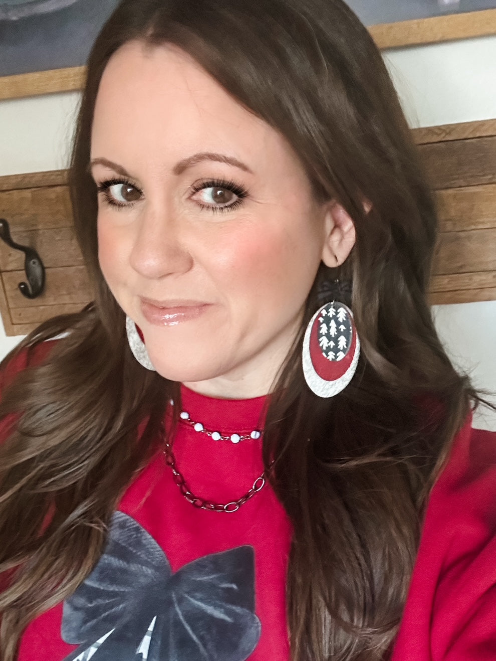 Close-up of woman wearing Heirloom Pines Earrings featuring red, white, and black layered leather with small black bows.