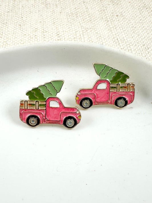small enamel stud earrings shaped like a pink and green holiday pickup truck carrying a Christmas tree on a light background