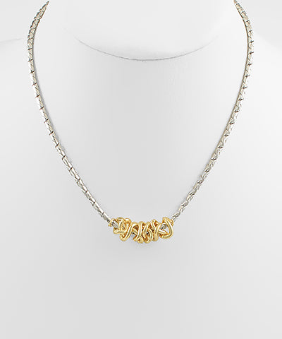 mixed metal necklace with silver chain and gold interlocking center displayed on white background