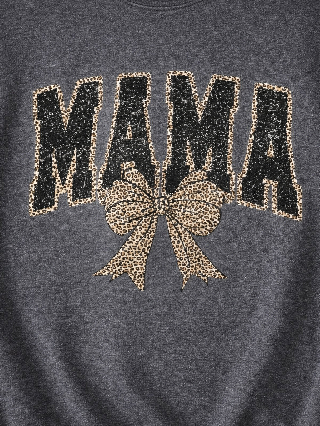 Close-up of charcoal MAMA graphic with black distressed faux sequin print, leopard outline, and leopard bow detail.