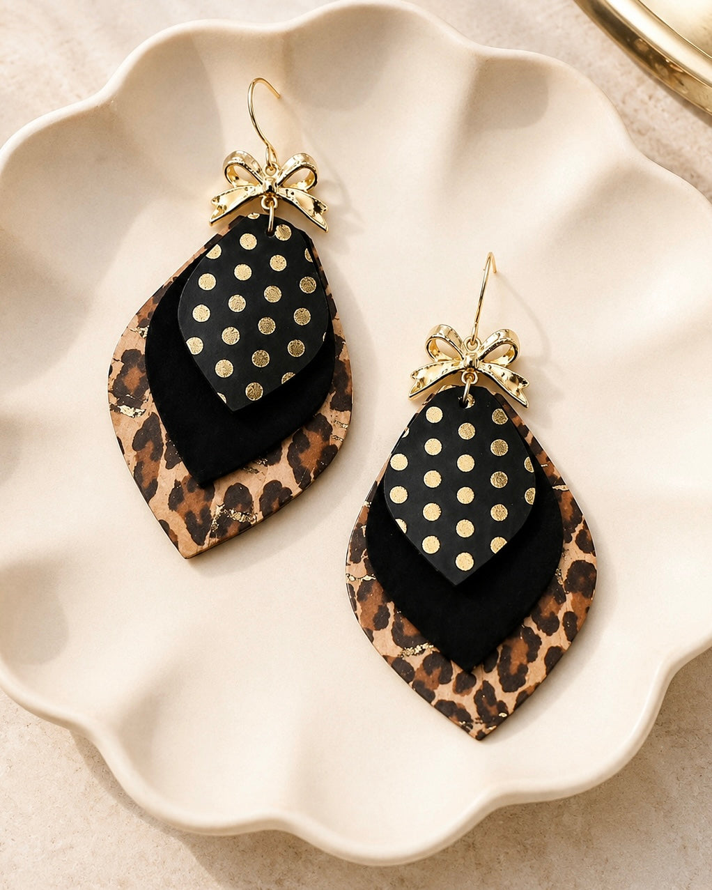 Leopard Glam Earrings with layered black, leopard print and metallic gold details on an ivory jewelry dish