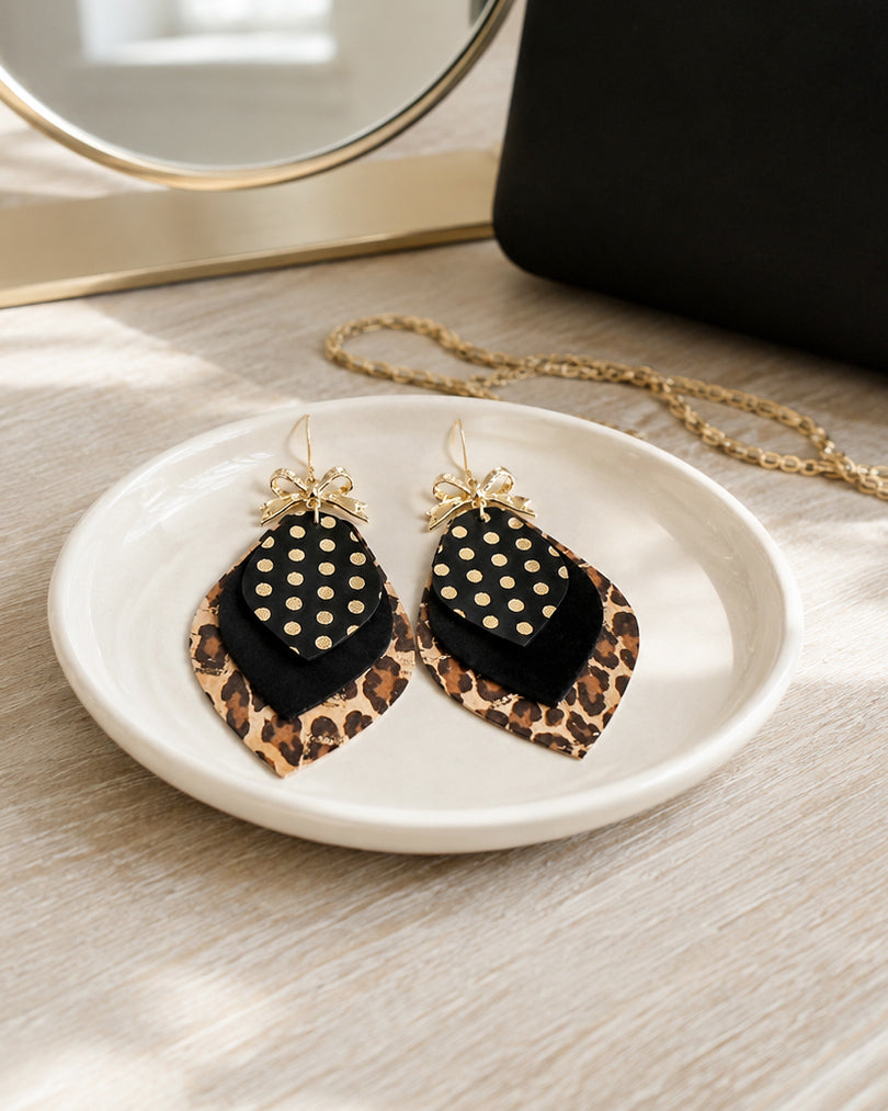 Leopard Glam Earrings styled on an ivory jewelry dish with black and gold accessories