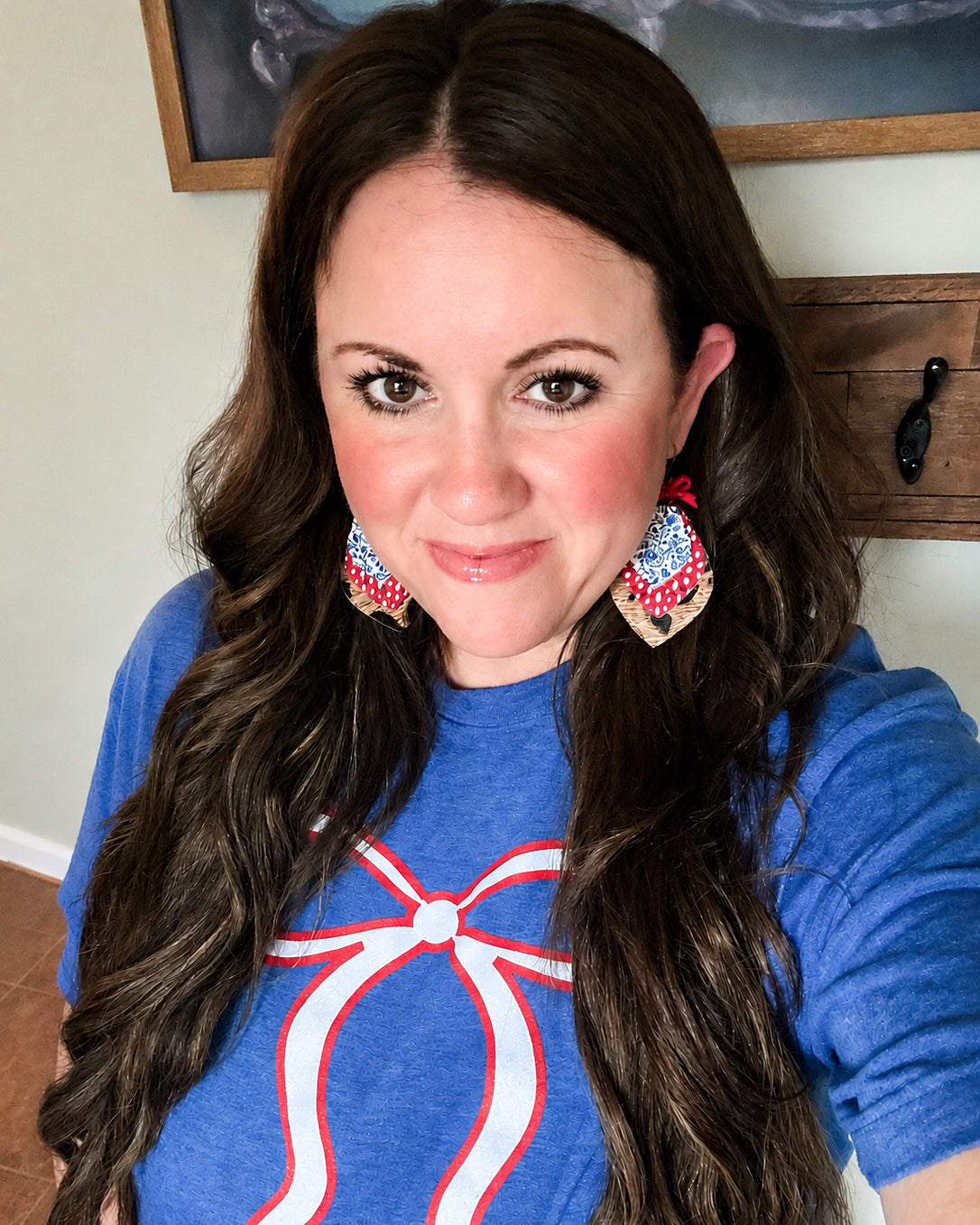 Liberty Belle Bow Tee modeled with American Honey Earrings, featuring a white bow graphic on a heather royal blue Tultex tee.