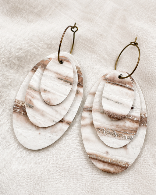 Linen Tide Earrings with three removable oval leather layers in ivory, taupe and warm brown marbling on soft ivory linen.