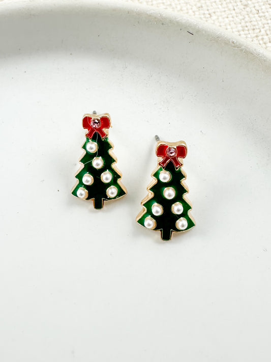 Small green Christmas tree stud earrings with gold trim, pearl accents, and a red bow on top displayed on a light background