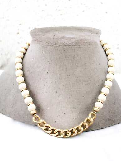 Ivory wood-bead necklace with a gold chain section displayed on a gray necklace stand.
