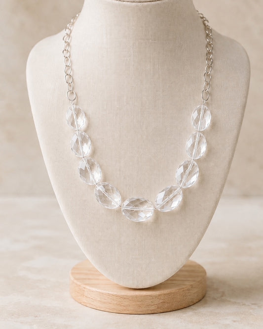 Moonlight silver statement necklace with clear faceted beads displayed on an ivory necklace stand