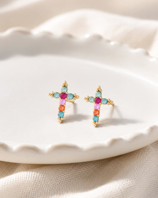Morning Joy cross stud earrings with colorful faceted stones and gold-tone details displayed in a white jewelry dish