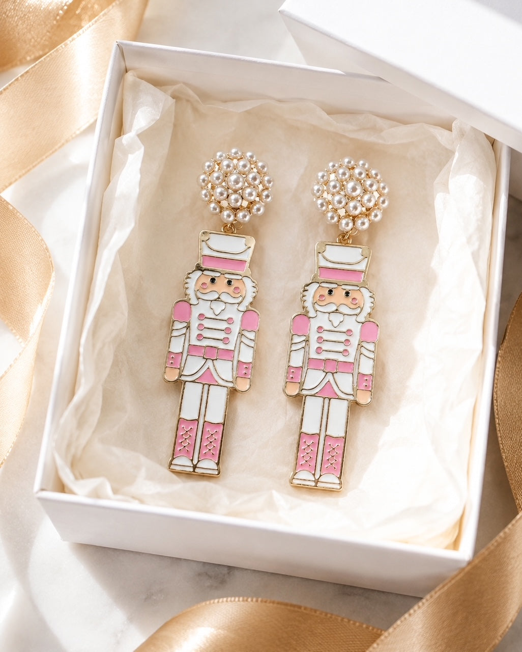 Blush pink nutcracker earrings presented in a white gift box with tissue paper.
