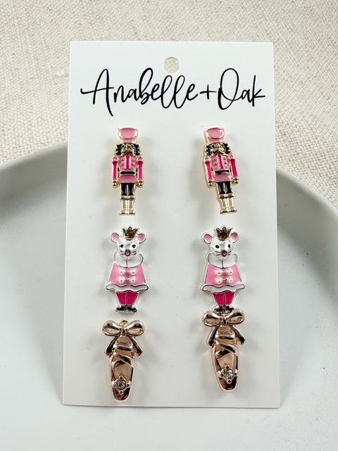 Close-up of Nutcracker, Rat King, and pointe shoe stud earrings in pink tones showing detailed design