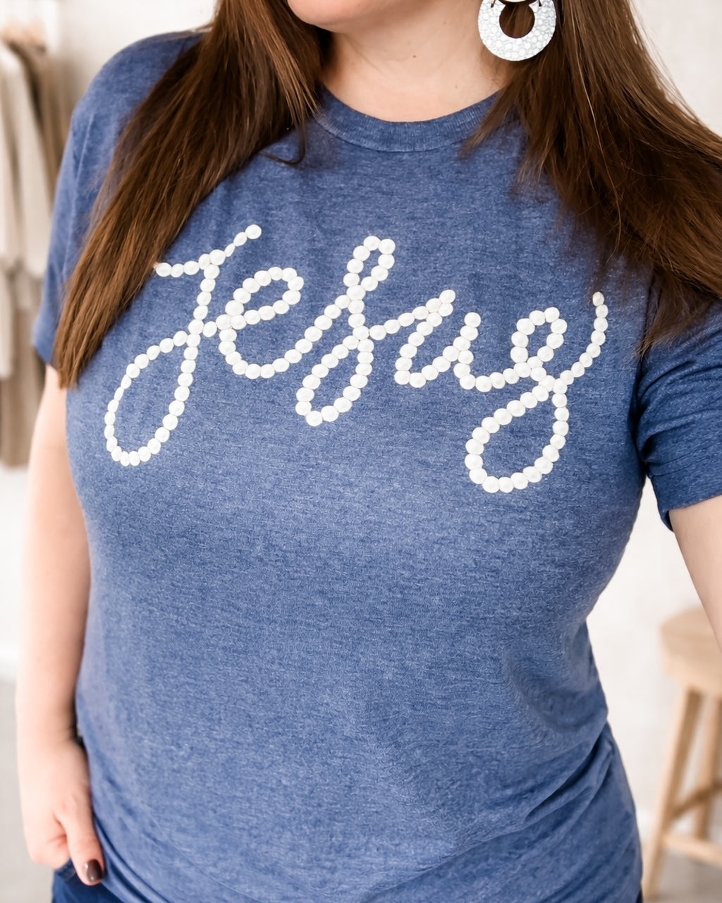 Model wearing heather navy graphic t shirt with white pearl style Jesus lettering