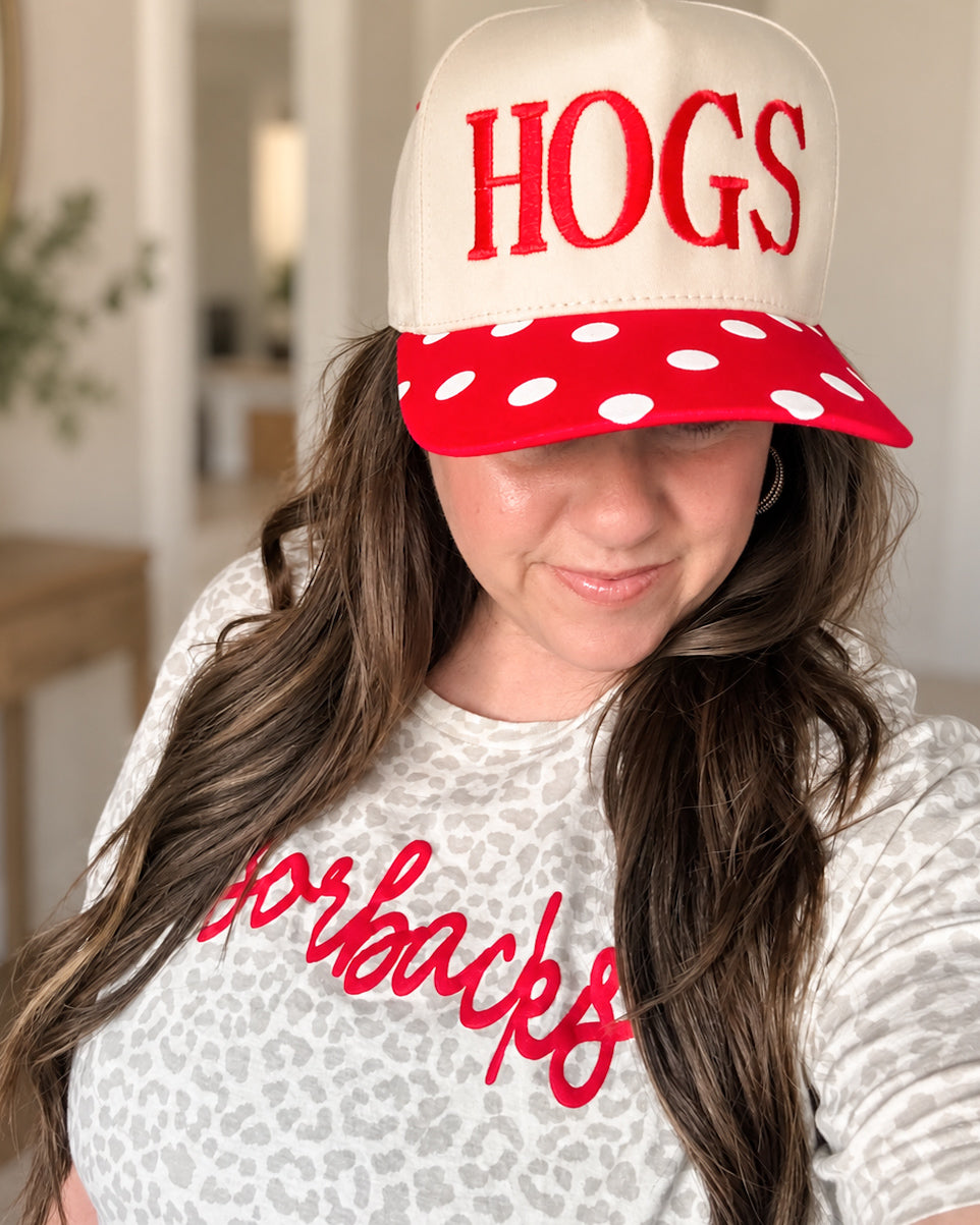 Woman wearing the red and cream HOGS Pep Rally Hat with a light leopard print Arkansas tee, showing how the hat sits when worn.