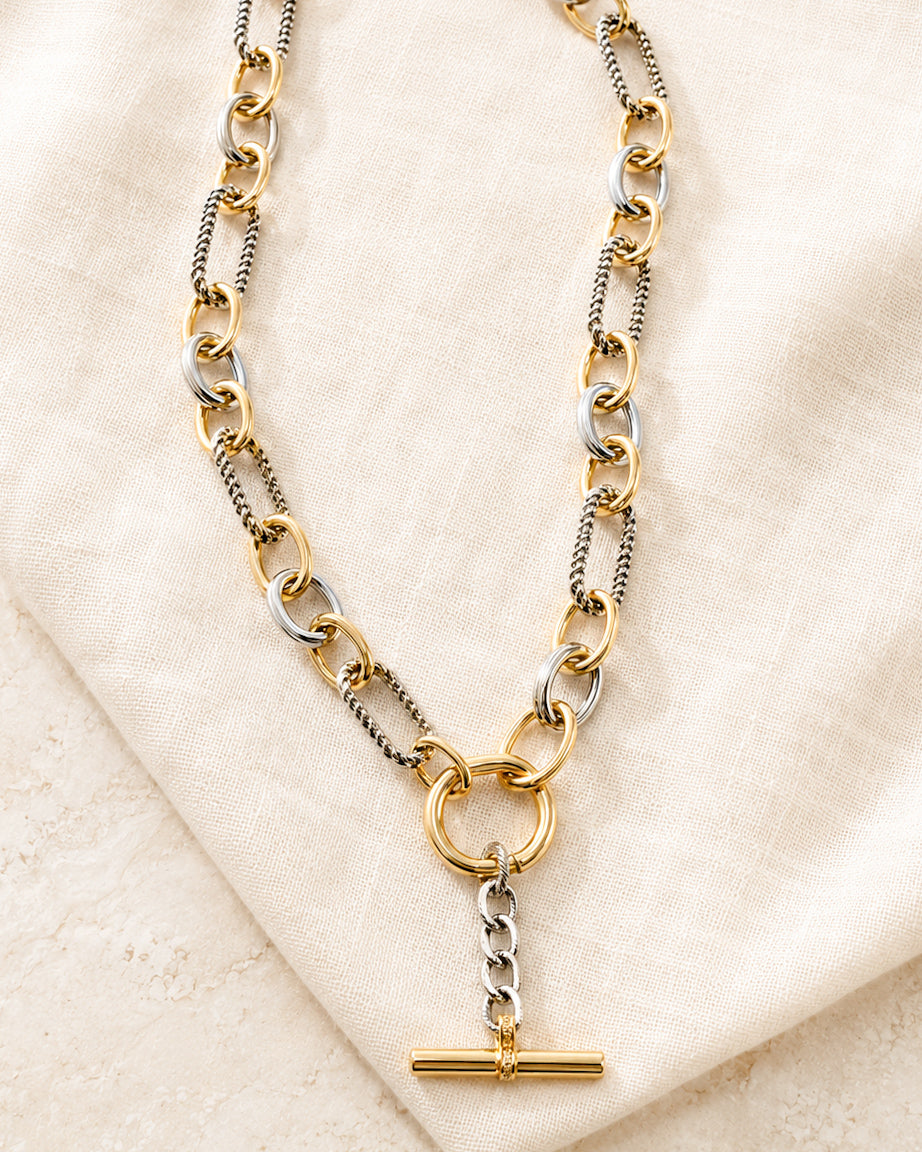 Plot Twist mixed metal Y necklace with gold and silver links and T-bar pendant styled on ivory linen