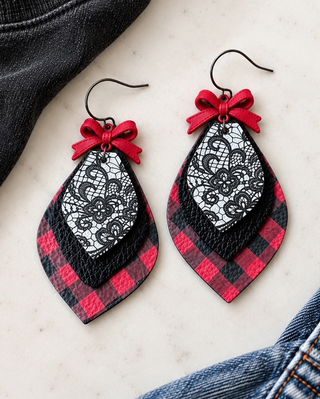 Pretty Little Rebel red bow earrings styled with black fabric and denim, featuring layered buffalo plaid leather, textured black leather, and black floral lace print.
