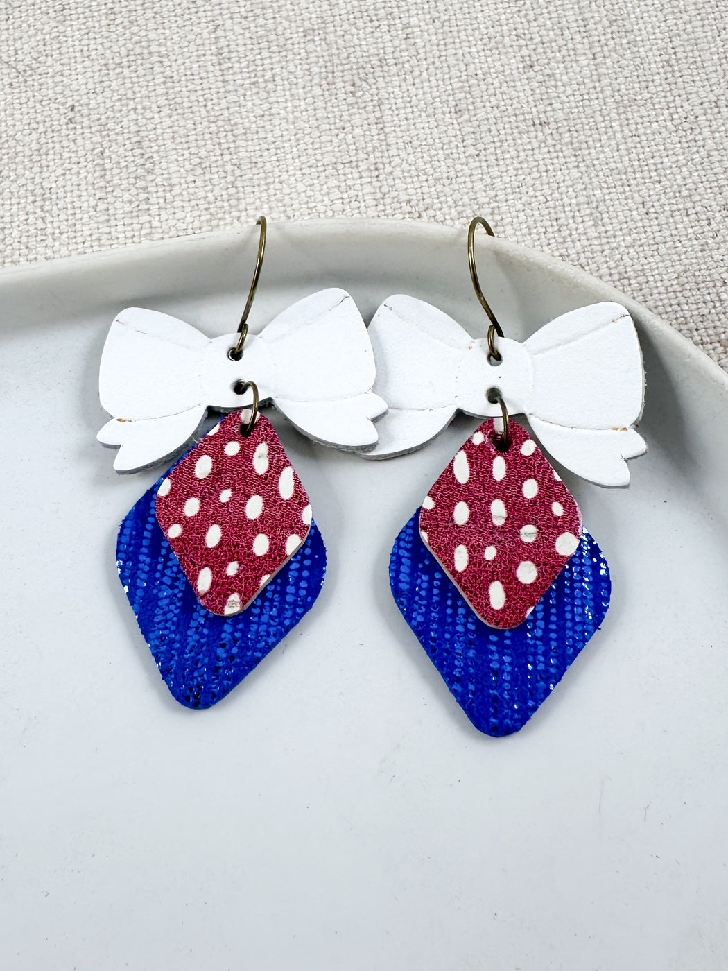 Red, White, & Cute Earrings featuring layered cork and genuine leather with a patriotic bow design and 2-inch drop.