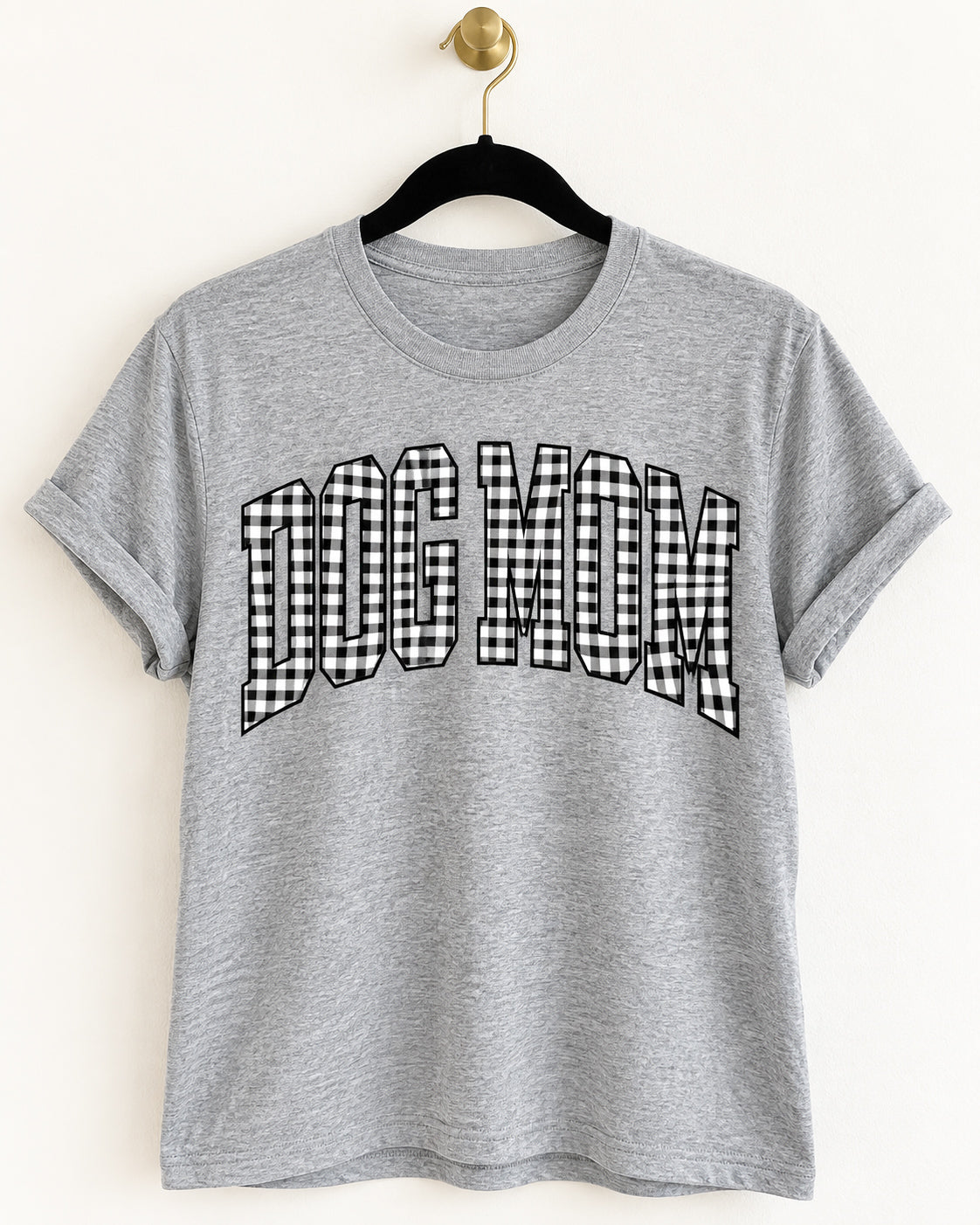Heather gray tee with oversized DOG MOM lettering in black and white gingham, hanging on a black velvet hanger.