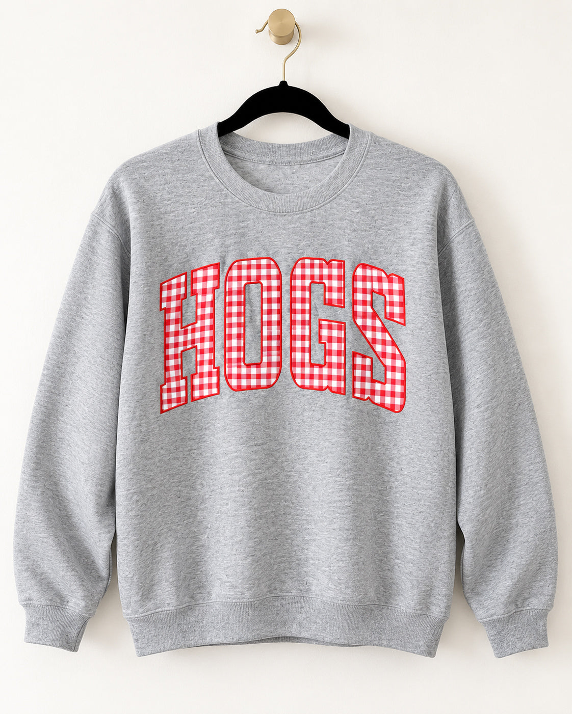 Sport gray crewneck sweatshirt with oversized HOGS lettering in red and white gingham, hanging on a black velvet hanger.