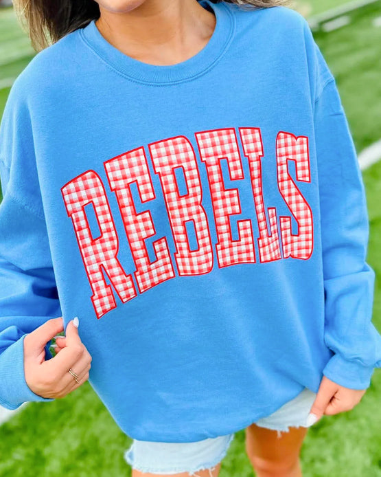Woman wearing a Carolina blue crewneck sweatshirt with oversized REBELS lettering in red and white gingham.