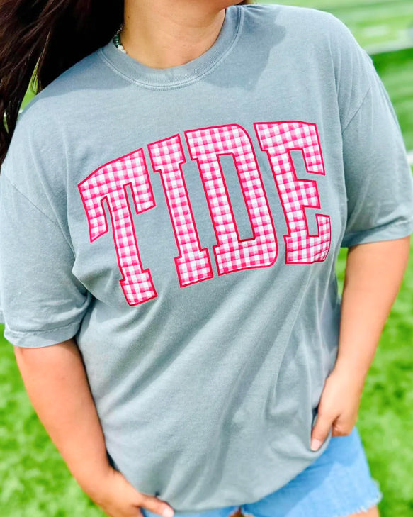 Woman wearing a gray tee with oversized TIDE lettering in red and white gingham.