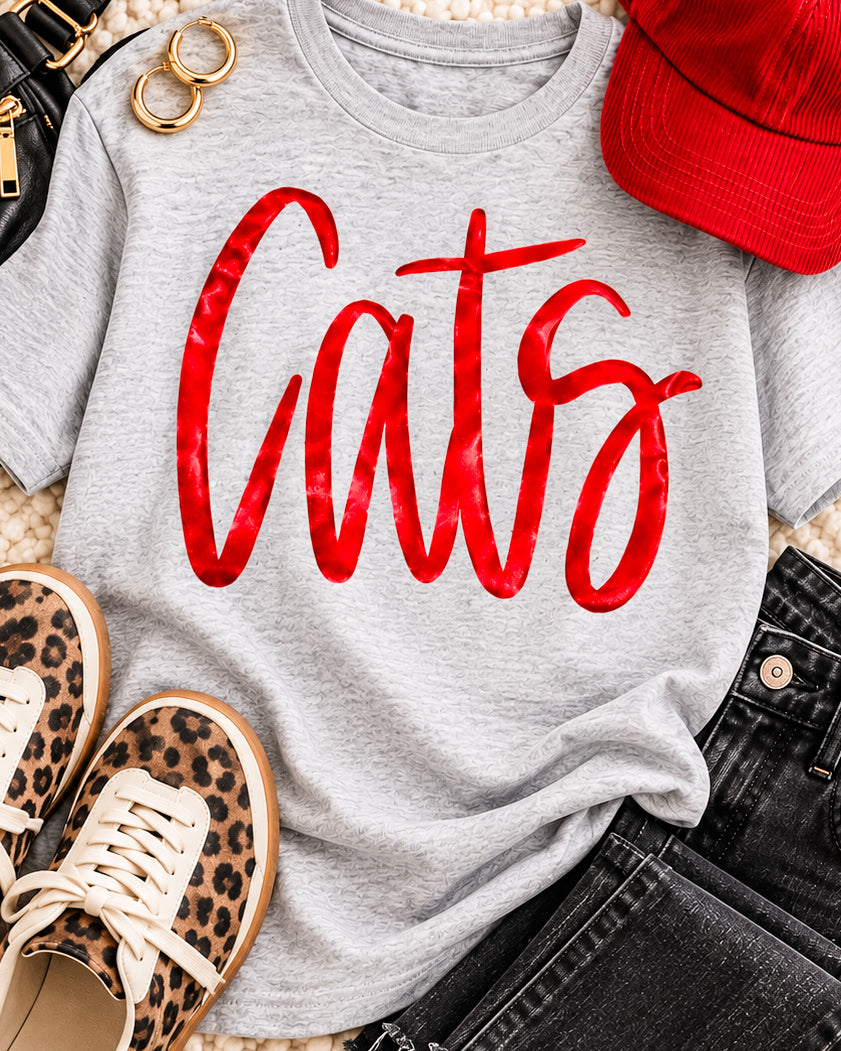 Gray Cats graphic tee with metallic red lettering styled with leopard sneakers, black jeans, red cap, and gold hoops.