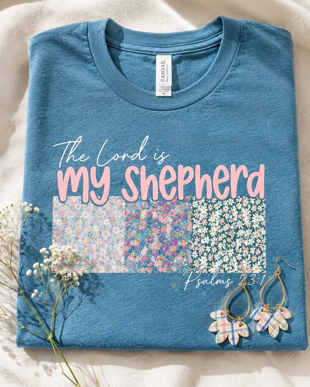 Close-up of the Shepherd's Garden Tee floral Psalm 23 graphic on heather deep teal Bella Canvas fabric.