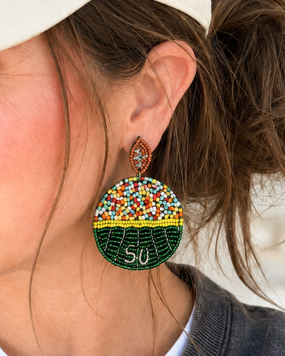 Model wearing Sideline Spirit football field seed bead statement earrings for size and fit.