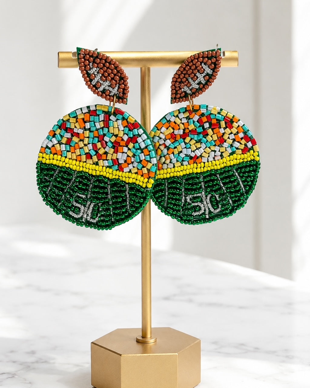 Sideline Spirit football field seed bead earrings displayed on a matte gold jewelry stand.