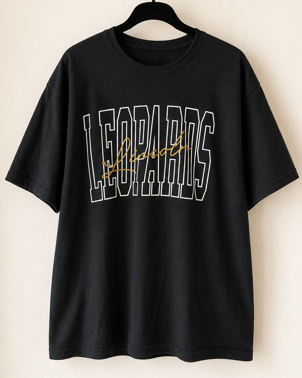 Black Lincoln Leopards sweatshirt styled with black leggings, leopard-print hat, white sneakers, and gold hoop earrings.