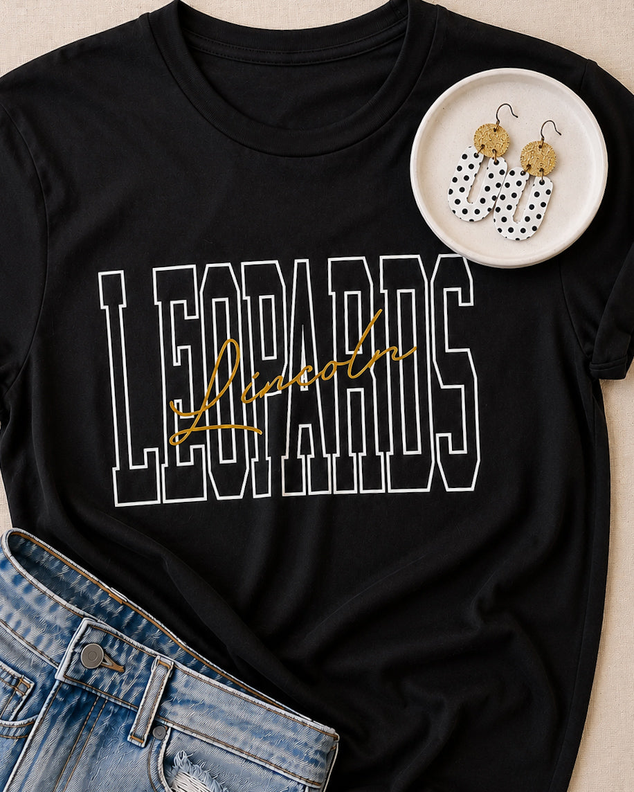 Black and white polka dot earrings styled with a black LEOPARDS graphic tee and denim for an easy coordinated outfit.