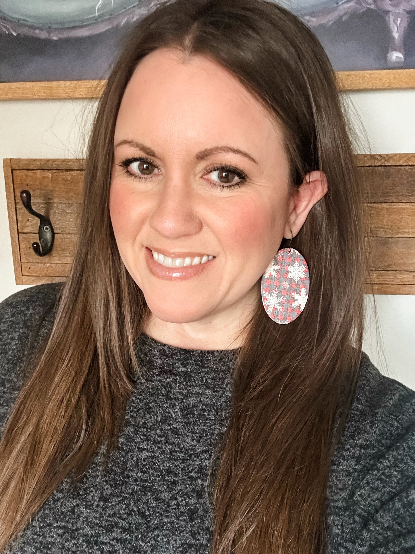Woman wearing large oval Snowflake & Flannel Cork dangle earrings in red and navy plaid with white snowflakes.