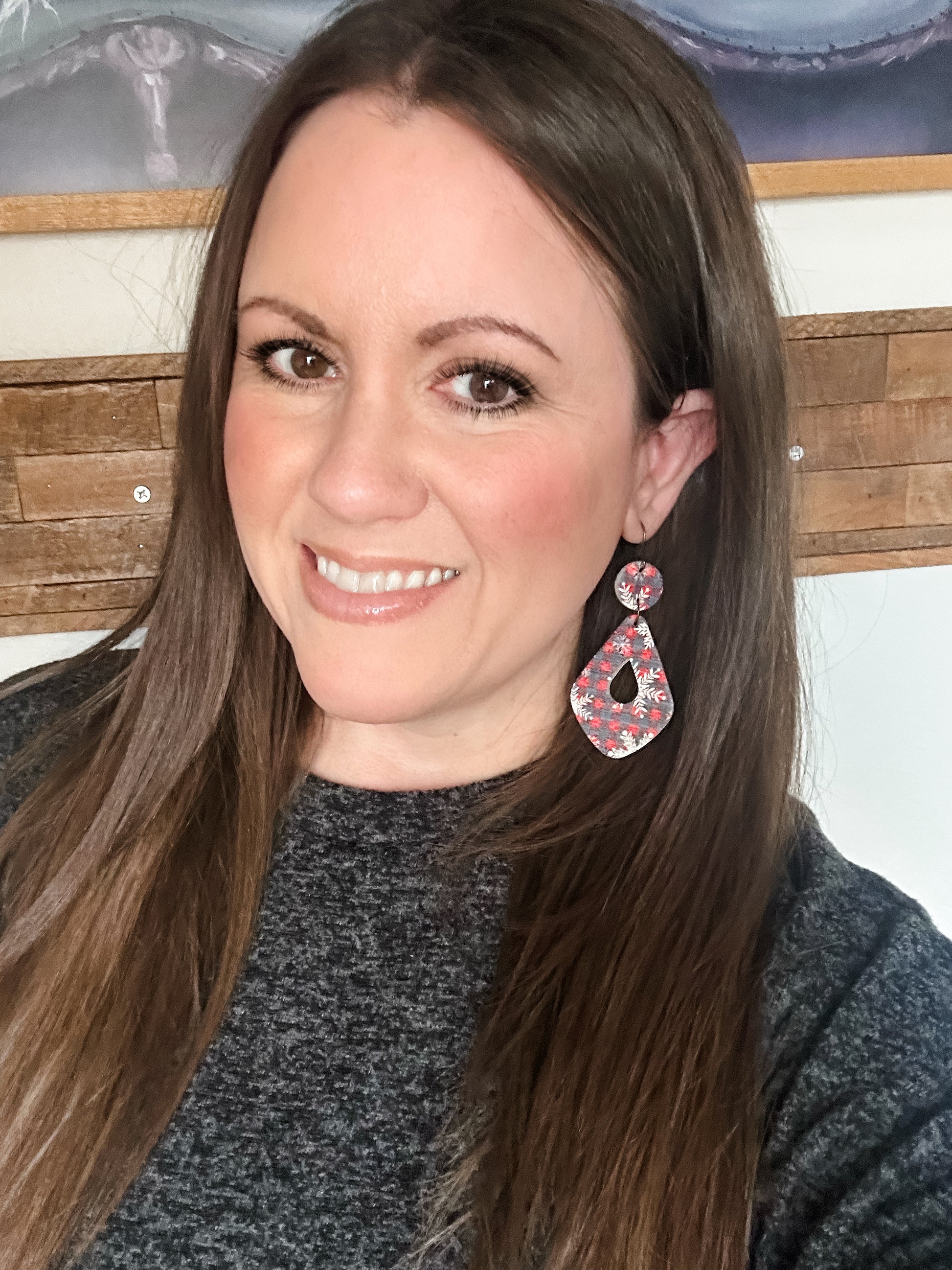 Woman wearing large Snowflake & Flannel Cork statement earrings in a red and navy flannel print with white snowflakes.