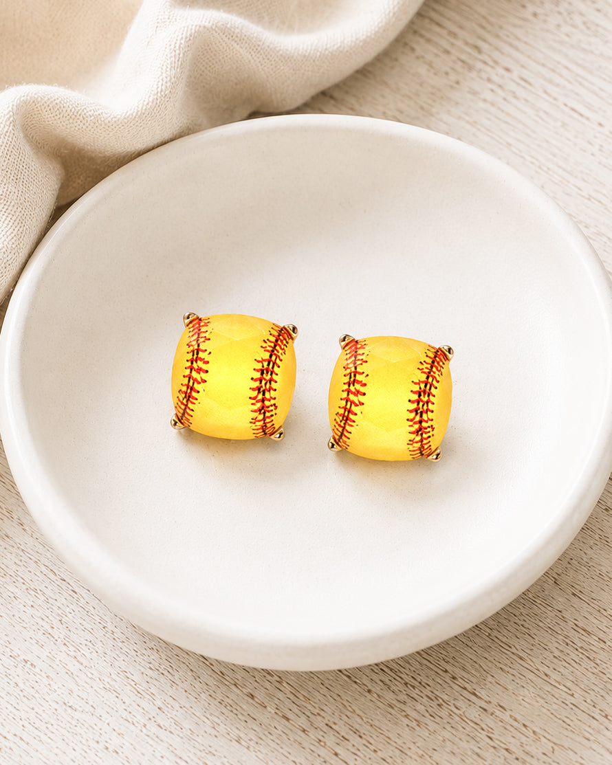 Yellow softball stud earrings in a faceted square setting displayed on a white ceramic jewelry dish.