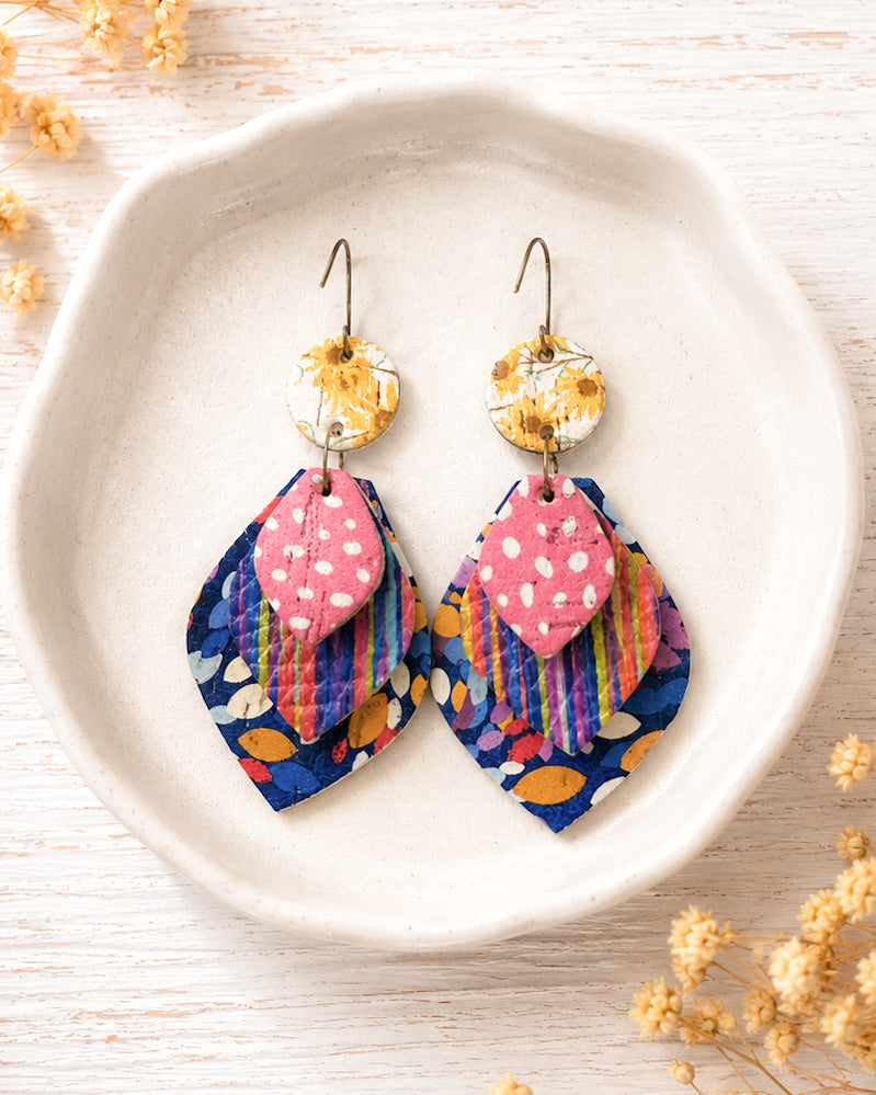 Colorful layered leather earrings displayed in an ivory jewelry dish showing the floral, striped and polka dot textures