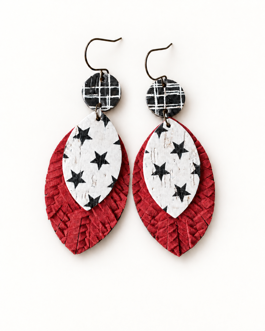 Starstruck handmade statement earrings with antique-bronze ear wires, black-and-white plaid circles, white star-print teardrops, and textured red leather layers on a white background.