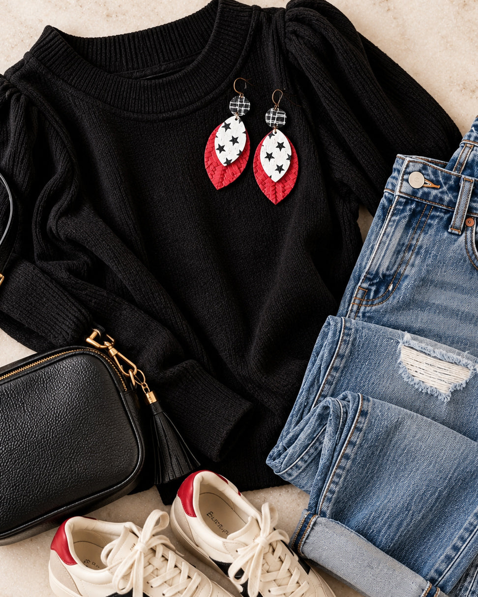 Starstruck handmade red, black, and white layered statement earrings styled with a black knit top, distressed blue jeans, black crossbody bag, and cream sneakers.