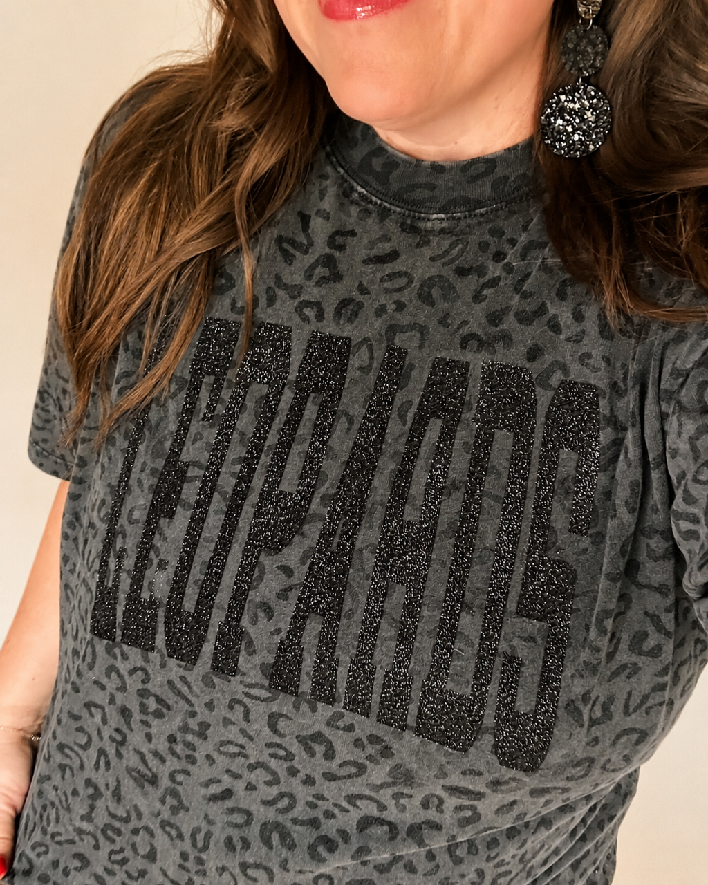 Woman wearing the black leopard print LEOPARDS graphic tee, showing the oversized fit and glitter lettering.
