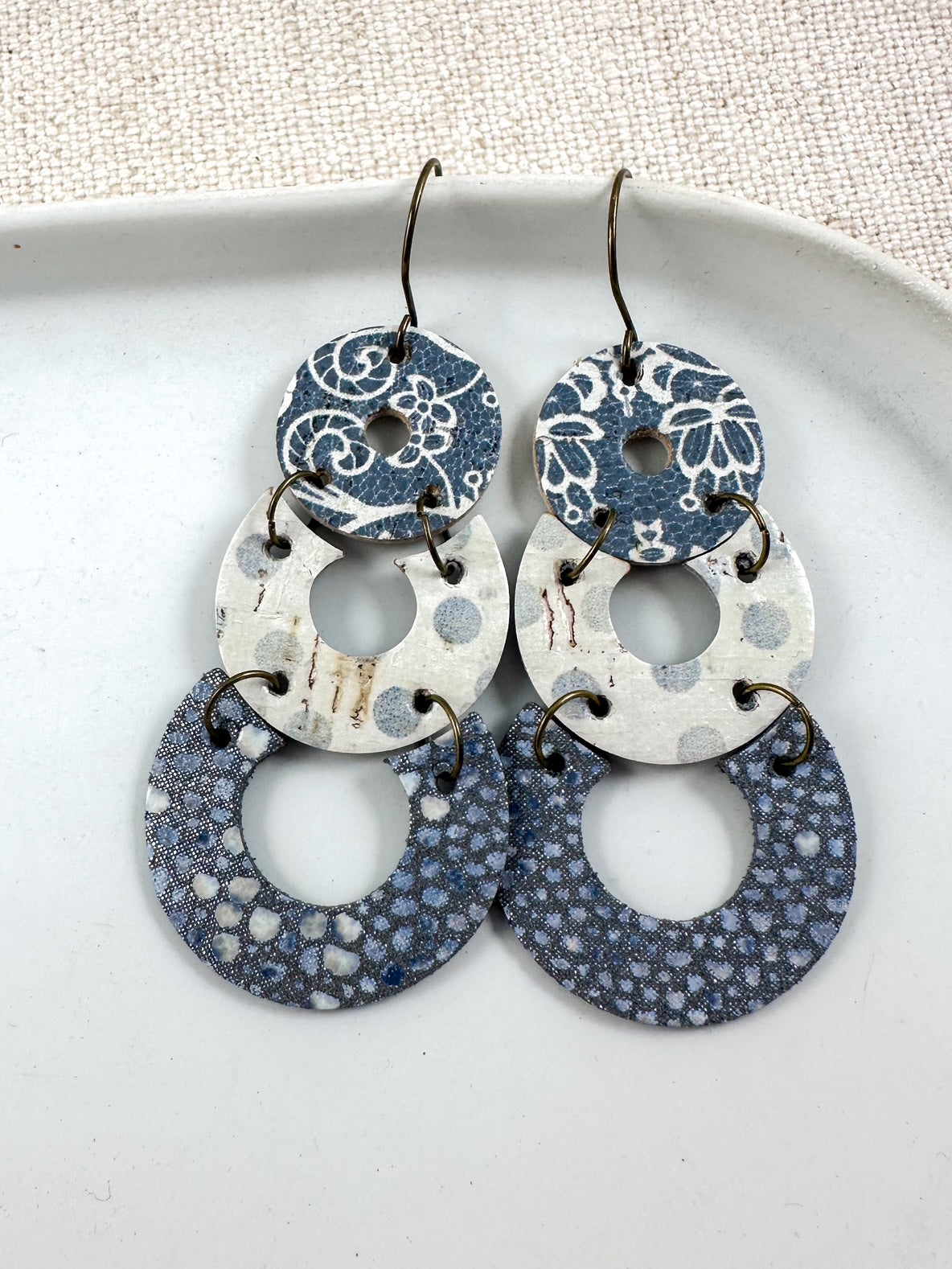 Layered genuine leather and cork earrings in gunmetal gray and ivory with mixed patterns and antique bronze fishhook ear wires.