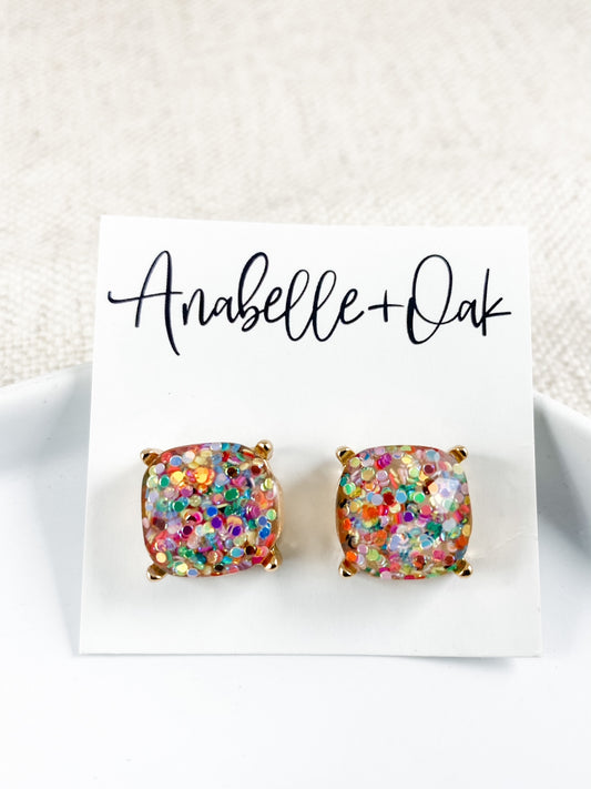 Colorful confetti resin stud earrings with gold prong setting in square shape.