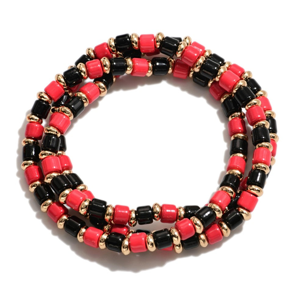 Set of three red and black beaded stretch bracelets with gold spacer bead accents arranged in stacked layers.